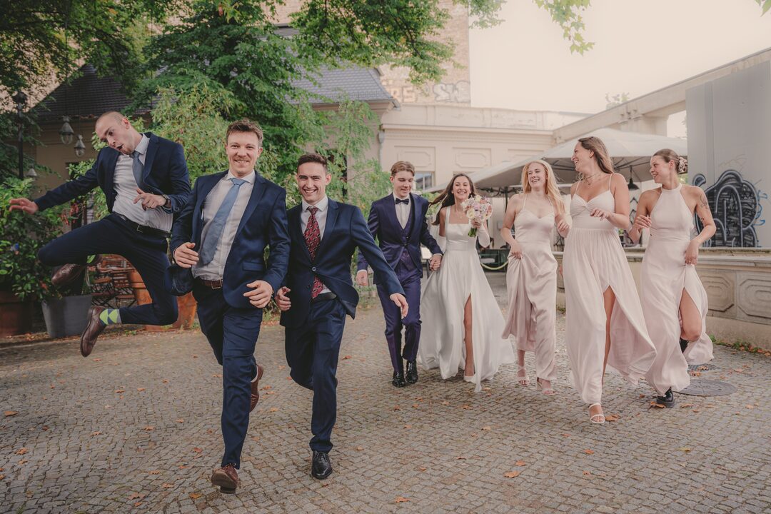 Die Hochzeitsgesellschaft läuft lachend über einen Hof