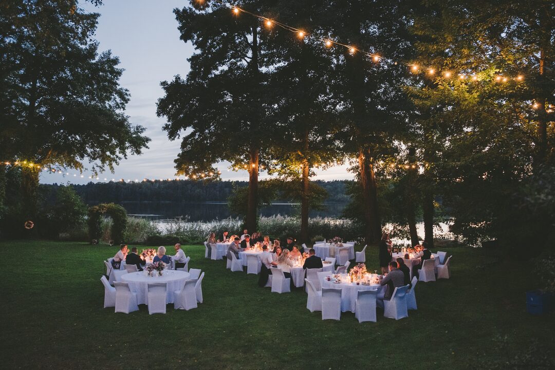 Abendliche Tafel unter Lichterketten am See in der blauen Stunde